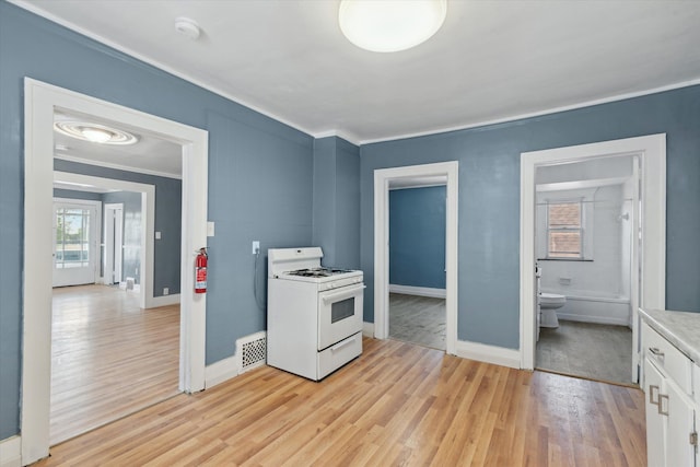 kitchen featuring crown molding, light wood-style flooring, white range with gas stovetop, and visible vents