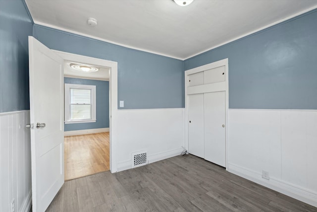 unfurnished room featuring wood finished floors and a wainscoted wall