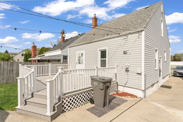 5125 Curtis St, Dearborn, MI 48126 - back of house featuring a shingled roof, a deck, a chimney, and fence