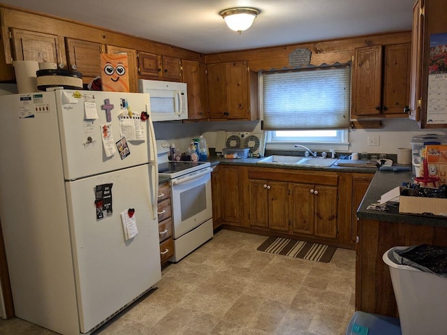 kitchen featuring white appliances, brown cabinetry, a sink, and dark countertops