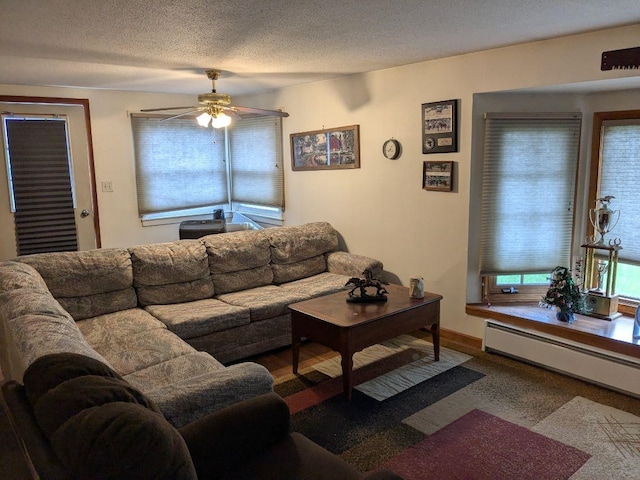carpeted living room featuring a baseboard radiator, ceiling fan, a textured ceiling, and baseboards