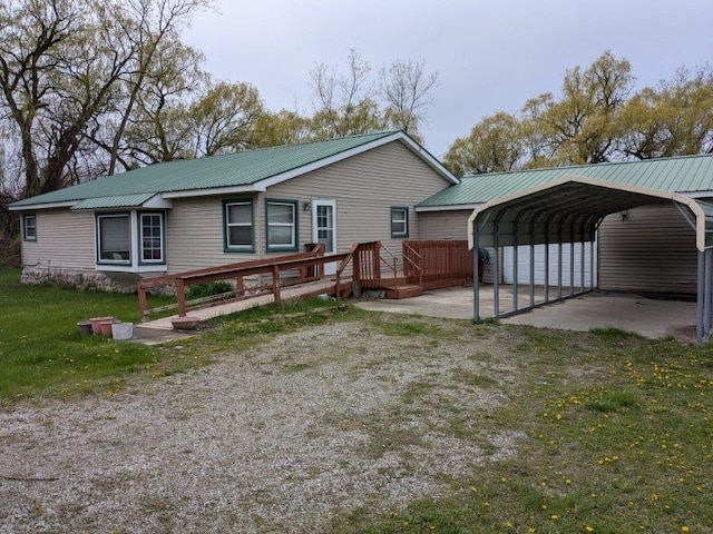 rear view of house with a carport, metal roof, a deck, and a yard