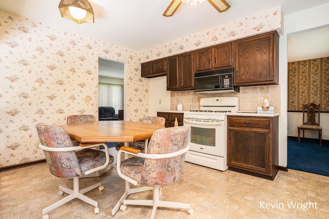 kitchen featuring gas range gas stove, dark brown cabinetry, black microwave, light countertops, and wallpapered walls