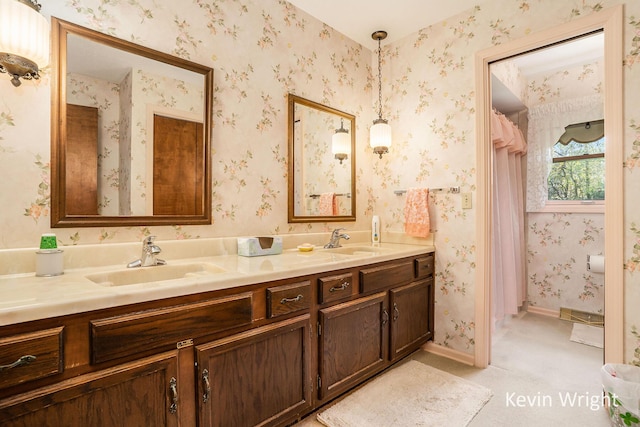 full bath featuring a sink, double vanity, and baseboards