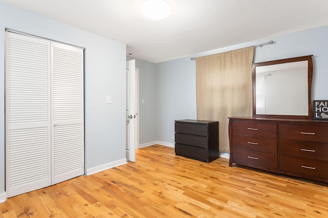 unfurnished bedroom featuring a closet, light wood-style floors, and baseboards