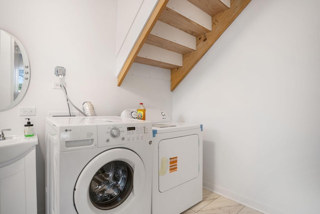 clothes washing area with separate washer and dryer, laundry area, marble finish floor, and a sink