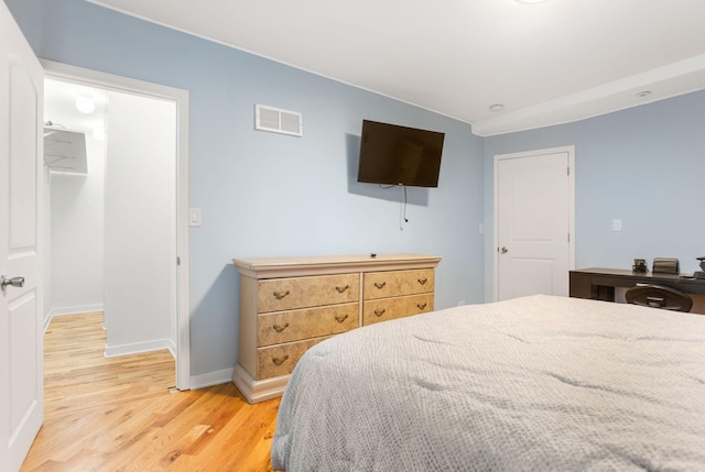 bedroom with light wood-style floors, visible vents, baseboards, and a spacious closet