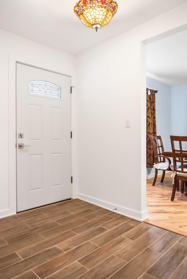 foyer featuring baseboards and dark wood-style floors