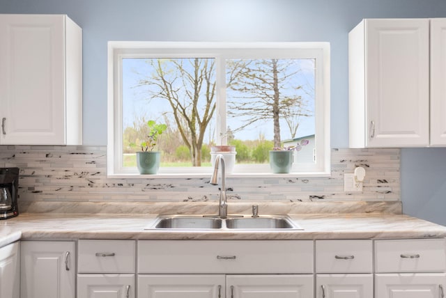kitchen featuring white cabinets, light countertops, tasteful backsplash, and a sink