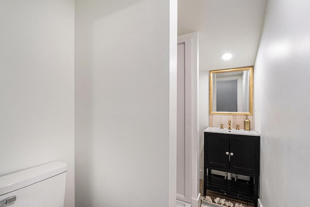 half bath with vanity, toilet, and recessed lighting