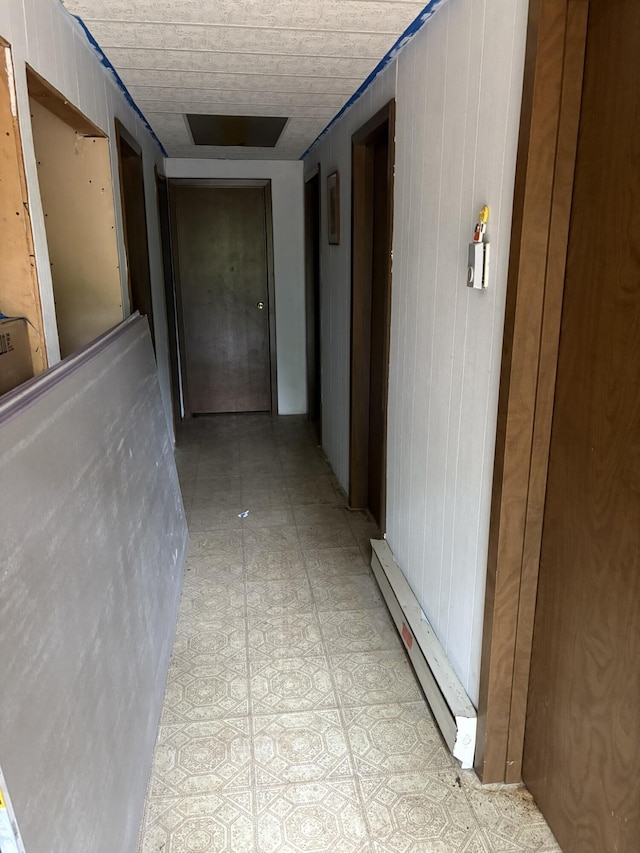 corridor featuring a baseboard radiator and wooden walls