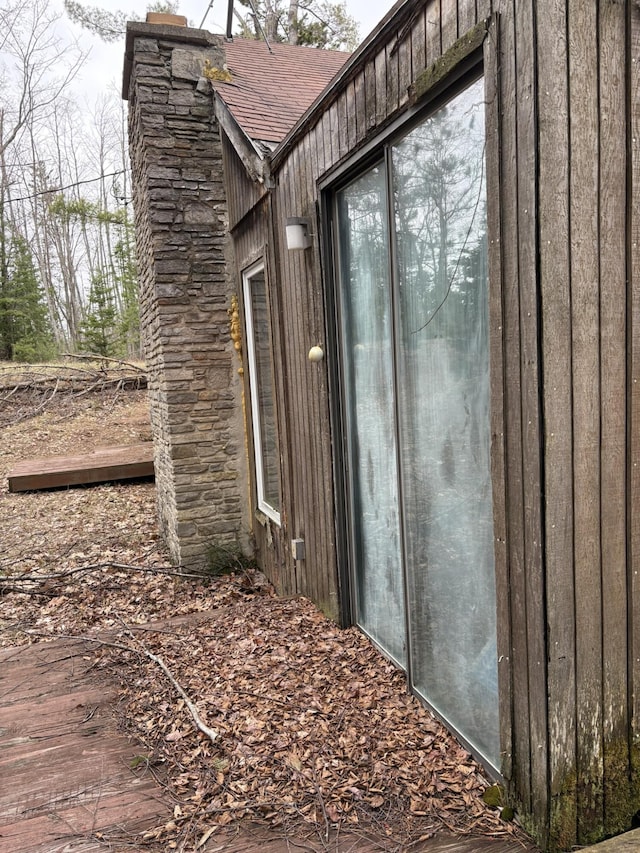 exterior space with a chimney and roof with shingles