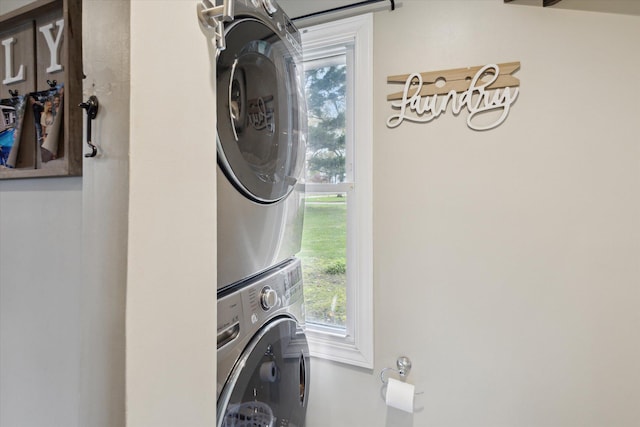 clothes washing area featuring laundry area, stacked washer / drying machine, and plenty of natural light
