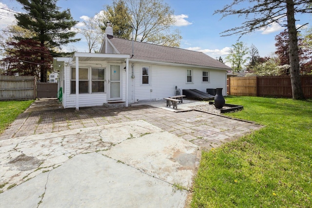 rear view of property with a fenced backyard, a patio area, a chimney, and a lawn