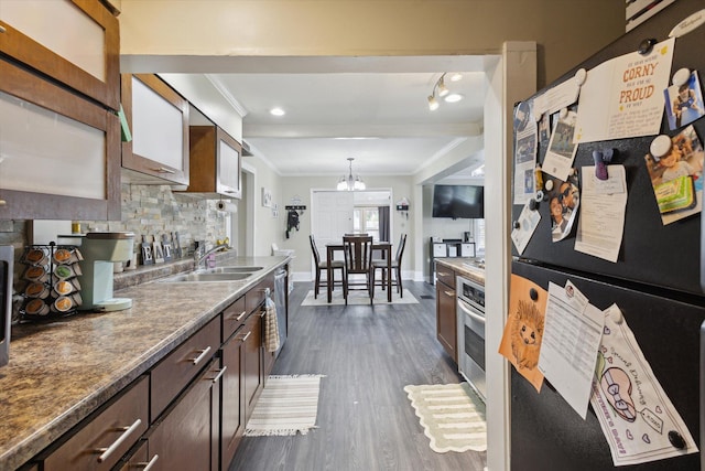 kitchen with a sink, crown molding, decorative backsplash, appliances with stainless steel finishes, and dark wood-style floors