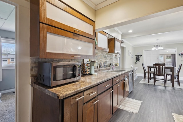kitchen with a sink, baseboards, appliances with stainless steel finishes, tasteful backsplash, and ornamental molding