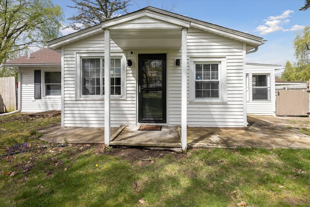 view of front of property with fence, a front lawn, and a patio area