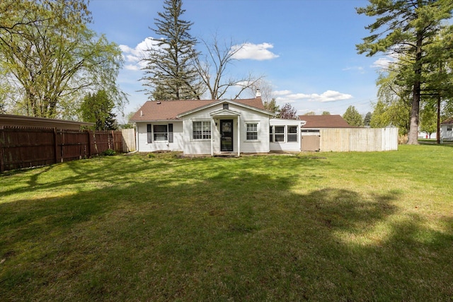 back of house with a yard, a chimney, and fence