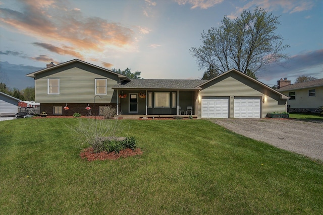 12441 Ray Rd, Ortonville, MI 48462 - split level home with an attached garage, asphalt driveway, a front yard, and a porch