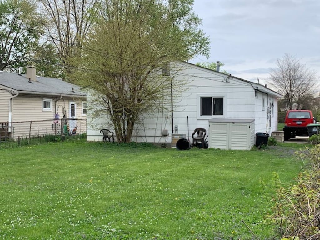 back of house featuring fence and a lawn