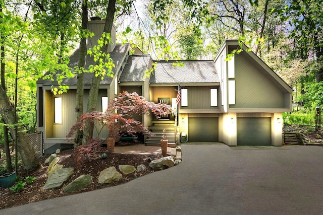 4943 Canyon Oaks Dr, Brighton, MI 48114 - view of front facade featuring asphalt driveway, a garage, a chimney, and a shingled roof