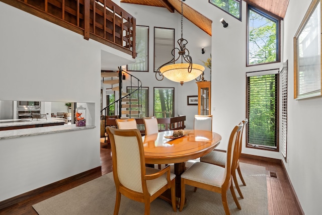 4943 Canyon Oaks Dr, Brighton, MI 48114 - dining room featuring a towering ceiling, dark wood finished floors, stairway, and baseboards