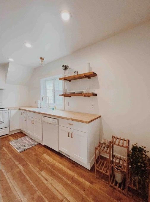 kitchen with light countertops, white cabinetry, light wood-style flooring, and white appliances