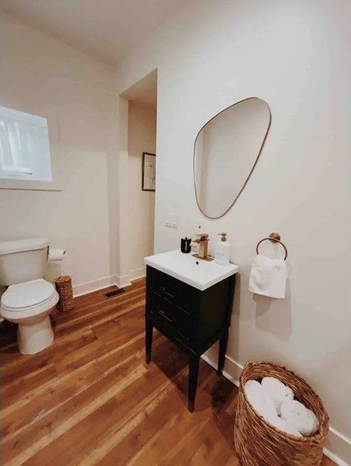 half bath featuring toilet, baseboards, vanity, and wood finished floors