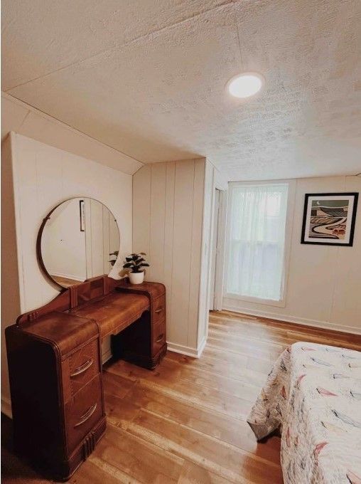 bedroom featuring a textured ceiling, wood finished floors, and baseboards