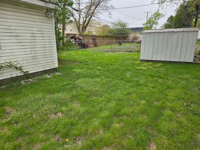 view of yard featuring an outdoor structure, fence, and a storage unit