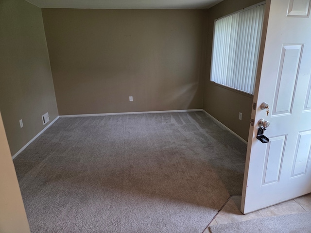 spare room with light carpet and baseboards