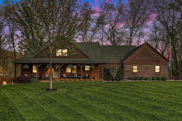 log cabin featuring covered porch, log exterior, and a lawn