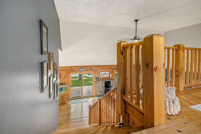 hallway featuring a textured ceiling, wooden walls, lofted ceiling, and hardwood / wood-style floors