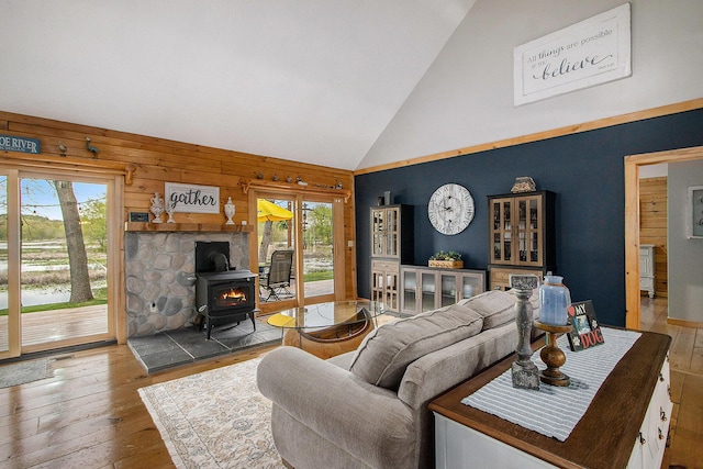 living room with a wood stove, plenty of natural light, wood-type flooring, and high vaulted ceiling