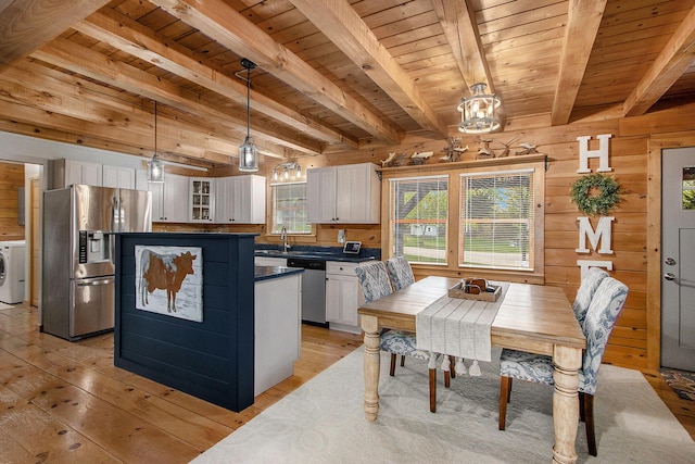 kitchen featuring stainless steel appliances, dark countertops, washer / dryer, and white cabinets