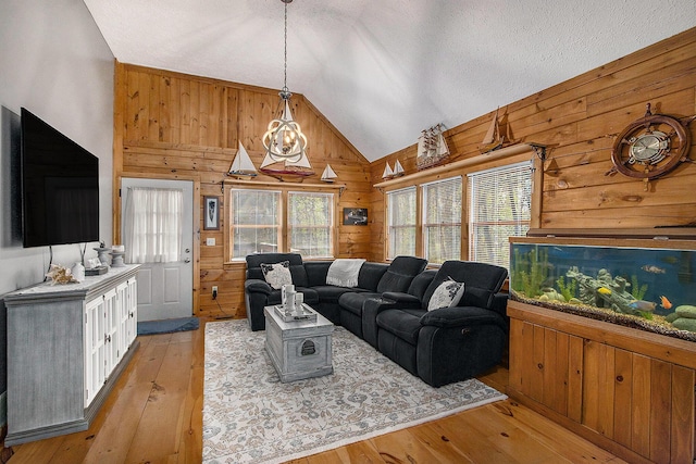 living area with vaulted ceiling, light wood finished floors, and wooden walls