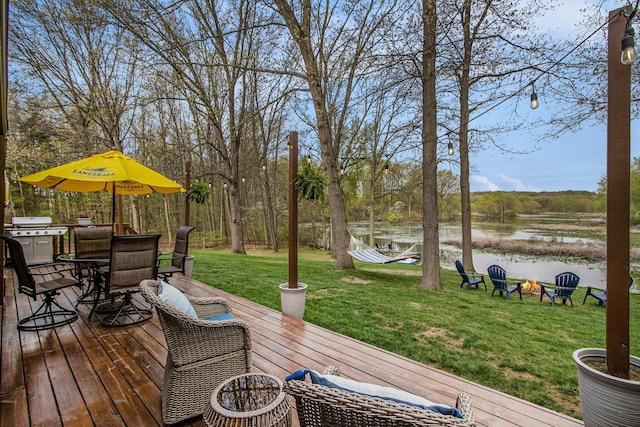 wooden deck featuring a water view, a fire pit, area for grilling, outdoor dining area, and a yard
