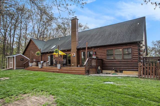 rear view of property with a yard, log exterior, a shed, an outbuilding, and a wooden deck