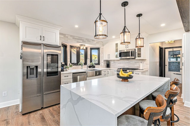 16511 Trailway Dr, Macomb, MI 48042 - kitchen with stainless steel appliances, a sink, white cabinetry, light wood-type flooring, and a center island