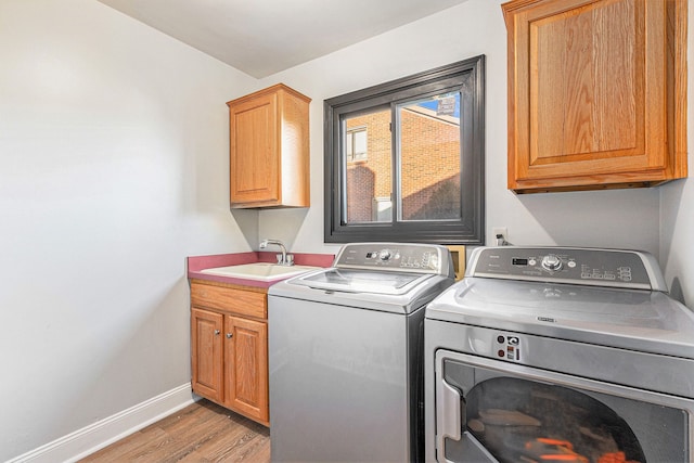 16511 Trailway Dr, Macomb, MI 48042 - laundry area with independent washer and dryer, cabinet space, light wood-type flooring, and baseboards