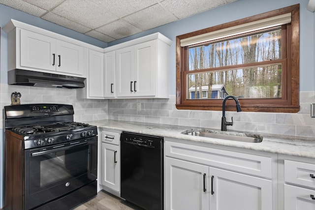 kitchen featuring a sink, white cabinets, black appliances, under cabinet range hood, and decorative backsplash
