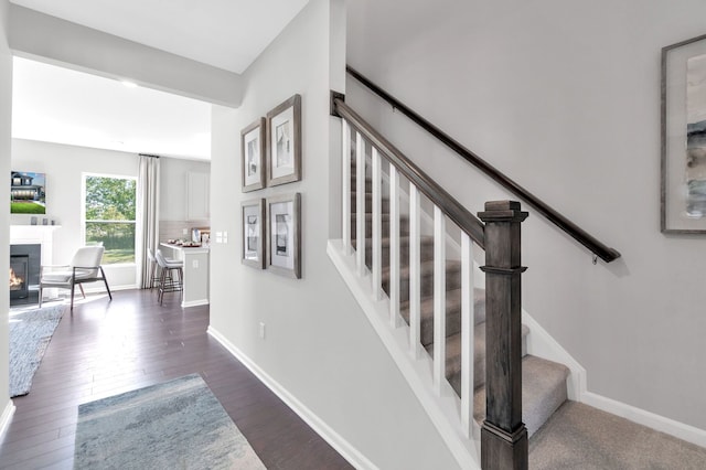 27142 Silo Dr, Saline, MI 48176 - staircase featuring wood finished floors and a glass covered fireplace