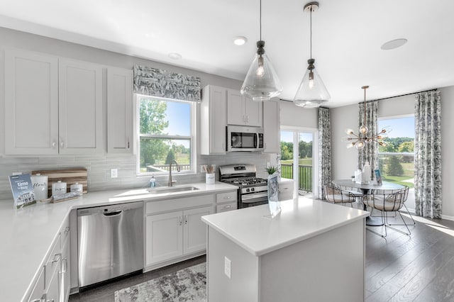27142 Silo Dr, Saline, MI 48176 - kitchen with appliances with stainless steel finishes, backsplash, a kitchen island, dark wood-type flooring, and light countertops