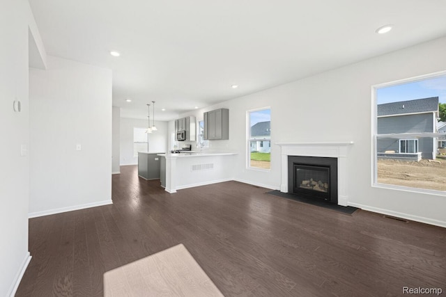 27142 Silo Dr, Saline, MI 48176 - unfurnished living room with dark wood finished floors, a fireplace with flush hearth, and recessed lighting