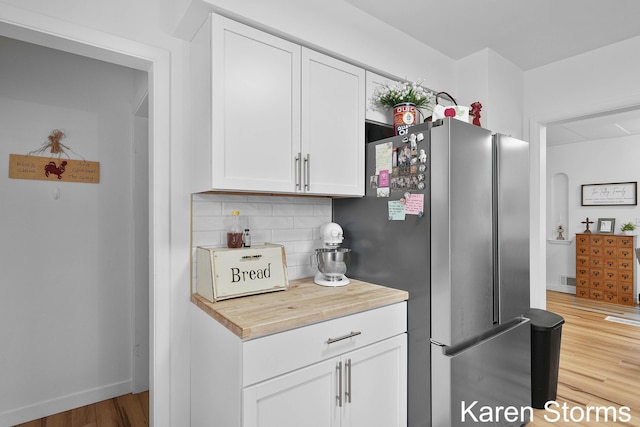 kitchen featuring freestanding refrigerator, light wood finished floors, tasteful backsplash, and white cabinets