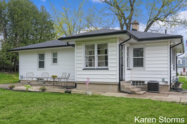 back of house with central AC, a chimney, a yard, roof with shingles, and a patio area