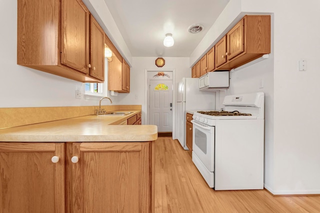 18377 Sunset St, Livonia, MI 48152 - kitchen featuring white appliances, a sink, light wood-style floors, light countertops, and a peninsula