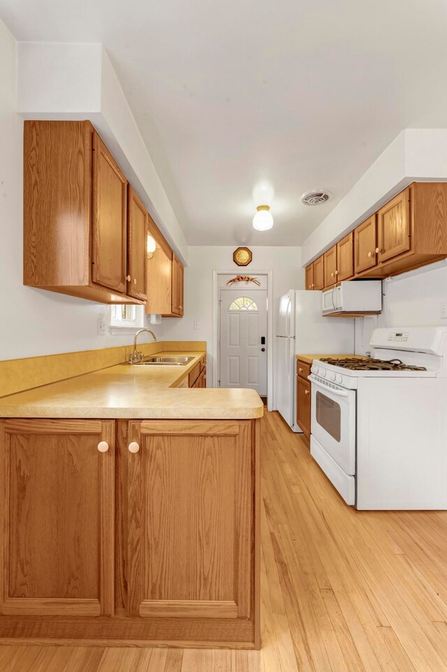 18377 Sunset St, Livonia, MI 48152 - kitchen featuring white appliances, a sink, a peninsula, light wood-style flooring, and light countertops