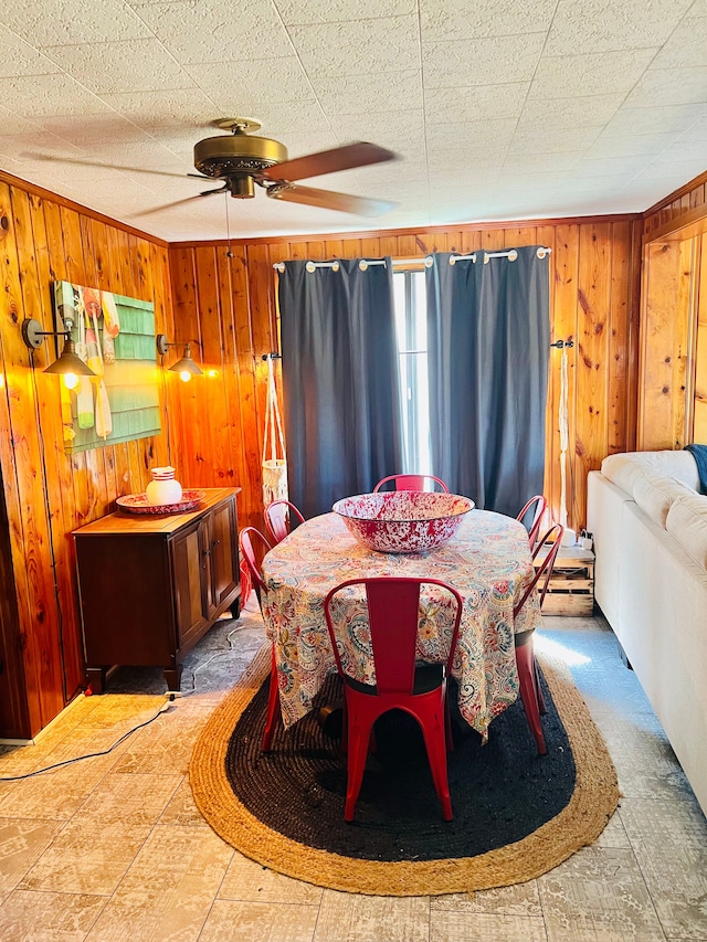 dining space with wood walls and ceiling fan