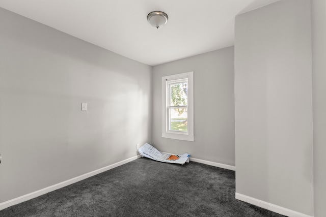 empty room featuring baseboards and dark carpet